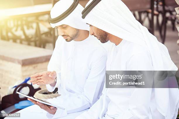 arab  businessmen in traditional clothes and tablet - middle east friends stock pictures, royalty-free photos & images