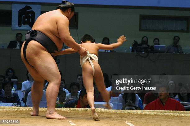 A professional sumo wrestler easy-handles a little boy during a pre- competition ceremony in Beijing, June 6 in Beijing, China. A total of 111 sumo...