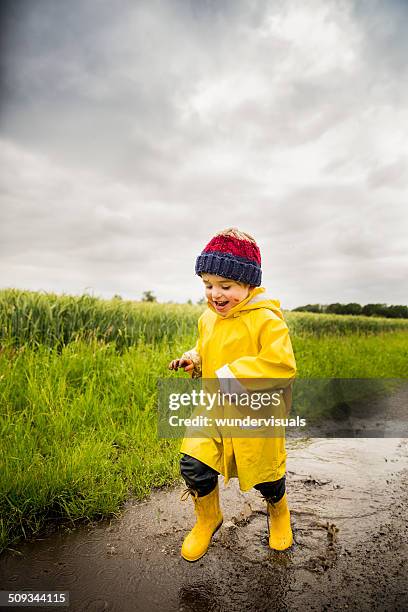 junge laufen durch big pfütze - puddle stock-fotos und bilder