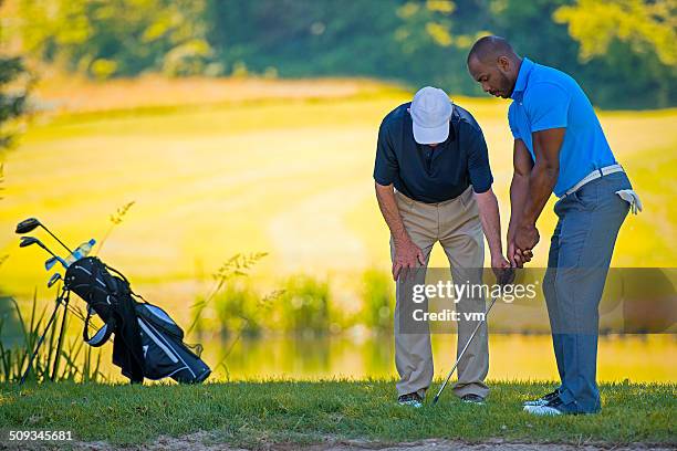 golf pro teaching male golfer - drivingrange stockfoto's en -beelden