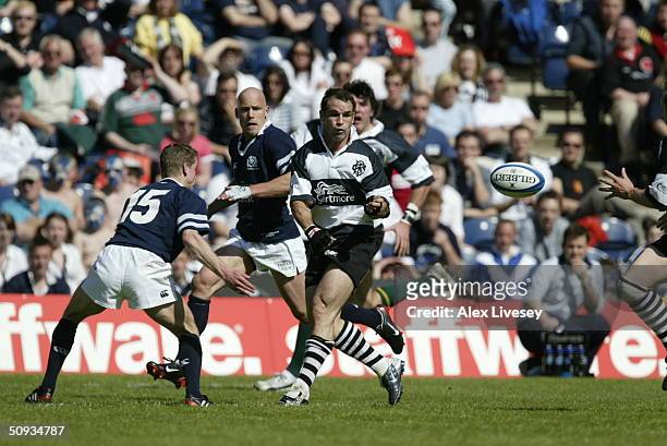 Mark Robinson of the Barbarians offloads as he is challenged by Scotland's Chris Paterson during the match between Scotland and the Barbarians held...