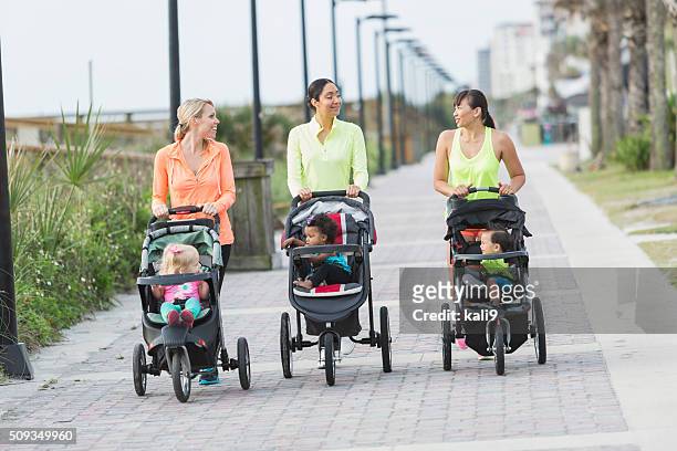multi-racial mothers with babies in jogging strollers - kinderwagen stockfoto's en -beelden