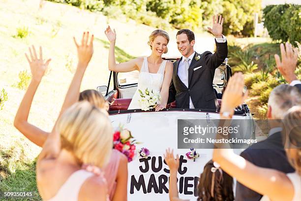 couple in car waving at people - just married car stockfoto's en -beelden