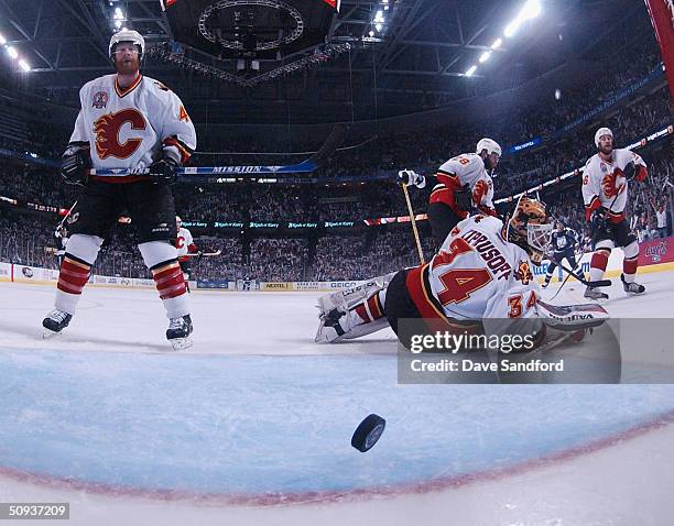 Goaltender Miikka Kiprusoff and other members of the Calgary Flames watch as a puck shot by Ruslan Fedotenko of the Tampa Bay Lightning exits the...