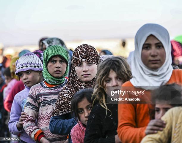 Syrians, flee the attacks of Syrian and Russian air forces wait in a queue to receive food, distributed by a Turkish NGO IHH Humanitarian Relief...