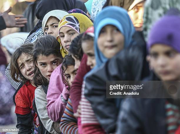 Syrians, flee the attacks of Syrian and Russian air forces wait in a queue to receive food, distributed by a Turkish NGO IHH Humanitarian Relief...