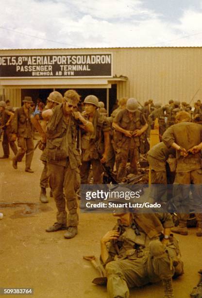 Large group of soldiers can be seen in their uniforms with full combat gear, doing their best to relax by socializing and smoking, awaiting...