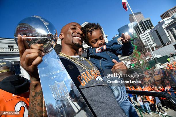 Denver Broncos Aqib Talib holds up the Super Bowl trophy with his child in hand, to the crowd on stage during the celebration. The Denver Broncos...