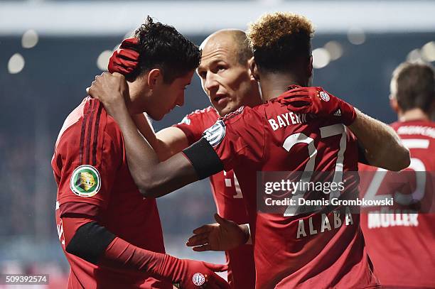 Robert Lewandowski of Bayern Muenchen celebrates scoring his side's first goal with Arjen Robben and David Alaba of Bayern Muenchen during the DFB...