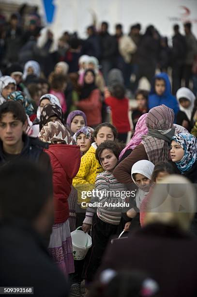 Syrians, who fled bombing in Aleppo, wait in a queue to get food at a tent city close to the Bab al-Salam border crossing on Turkish-Syrian border...