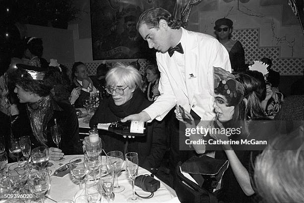 Andy Warhol celebrates his last New Year's Eve as a waiter pours champagne during a dinner at Cafe Roma restaurant in New York City, New York on...