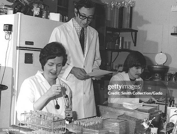 Female lab technicians reading and checking serologies to determine presence of influenza A/NJ/8/76 and registering antibody rise to the swine...