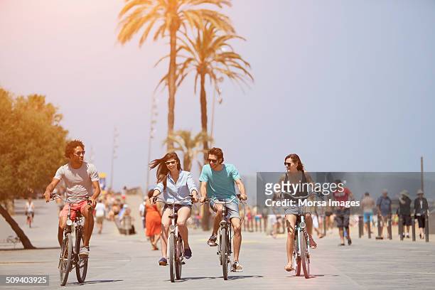 friends riding bicycles during summer vacations - provincie barcelona stockfoto's en -beelden