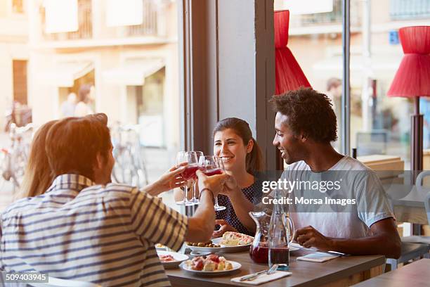 Friends toasting wine glasses at restaurant table