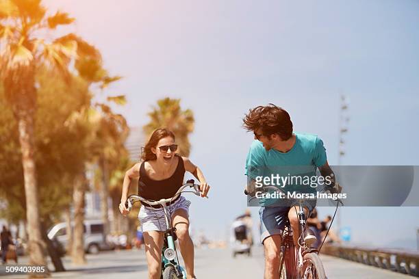 woman chasing man while riding bicycle - fun stock-fotos und bilder
