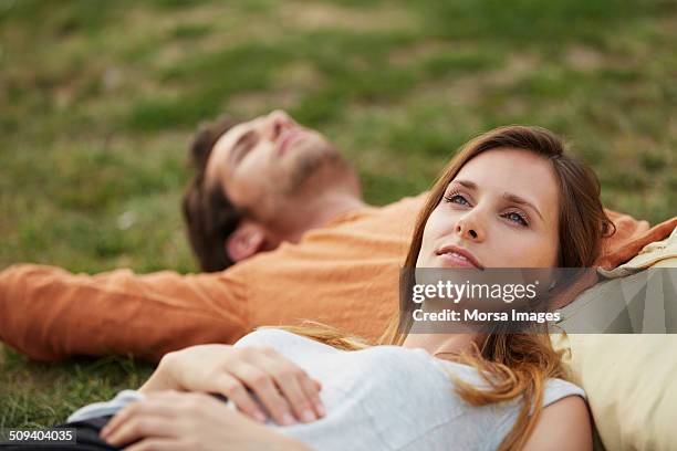 woman resting head on man's stomach at park - quiet contemplation foto e immagini stock