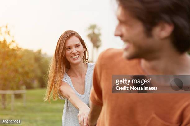 playful woman looking at man in park - couple walking in park stock pictures, royalty-free photos & images