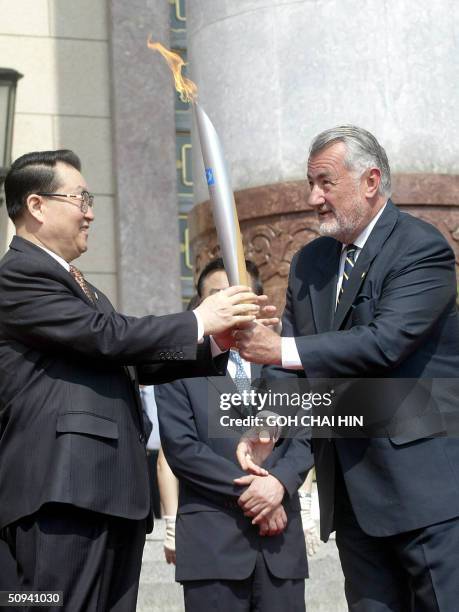 Li Changchun , a member of China's politburo, receives the Olympic flame from Marton Simitsek, vice president of Athens Olympic Committee, on the...