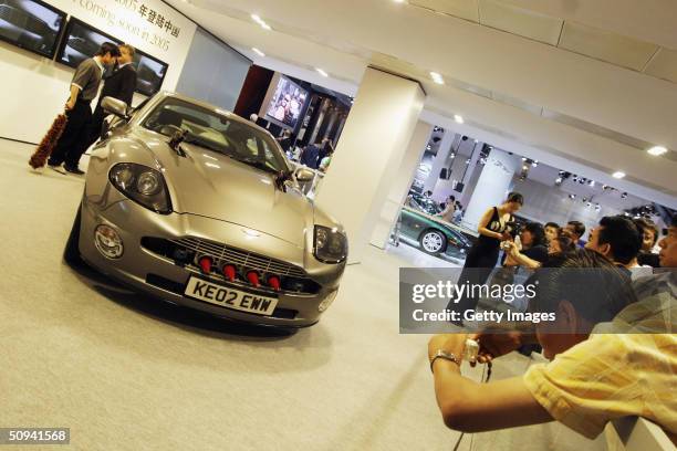 Visitors take pictures a specially customised 'James Bond' Aston Martin at AutoChina 2004 on June 9 in Beijing, China. Foreign auto manufacturers...