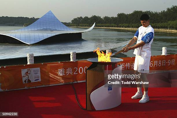 Torchbearer Yao Ming of the NBA Houston Rockets lights a cauldron with the Olympic Flame during Day 6 of the ATHENS 2004 Olympic Torch Relay on June...