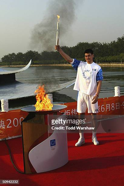 Yao Ming of the NBA Houston Rockets holds aloft the Olympic Flame at the Summer Palace during Day 6 of the ATHENS 2004 Olympic Torch Relay on June 9,...