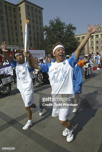 Torchbearers Yu and Quan carry the Olympic Flame through Qinghua University during Day 6 of the ATHENS 2004 Olympic Torch Relay on June 9, 2004 in...