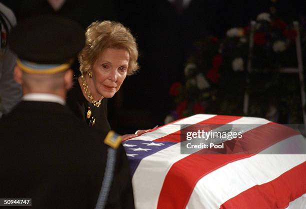 Former first lady Nancy Reagan touches the casket of her husband, former U.S. President Ronald Reagan, during his state funeral on Capitol Hill June...