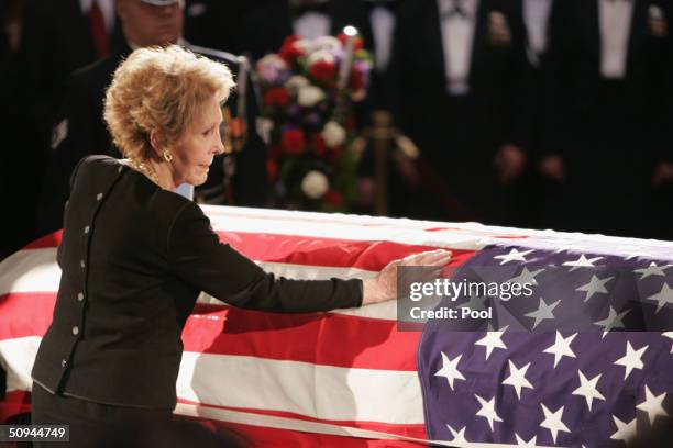 Former first lady Nancy Reagan touches the casket of her husband, former U.S. President Ronald Reagan, during his state funeral on Capitol Hill June...