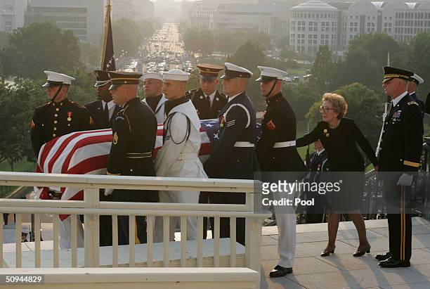 Former first lady Nancy Reagan touches the casket of her husband, former U.S. President Ronald Reagan, as the casket is carried towards the rotunda...