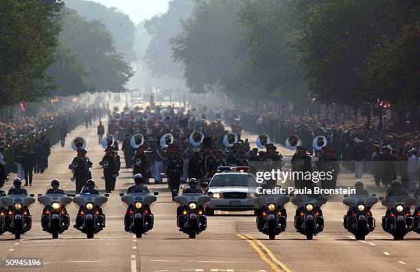 Policemen on motorcycles drive ahead of the horse drawn procession as it makes its way down Constitution Avenue enroute to the Capitol June 9, 2004...