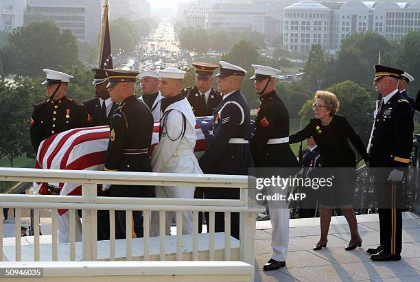 Former first lady Nancy Reagan touches the casket of her husband, former U.S. President Ronald Reagan, as the casket is carried towards the rotunda...