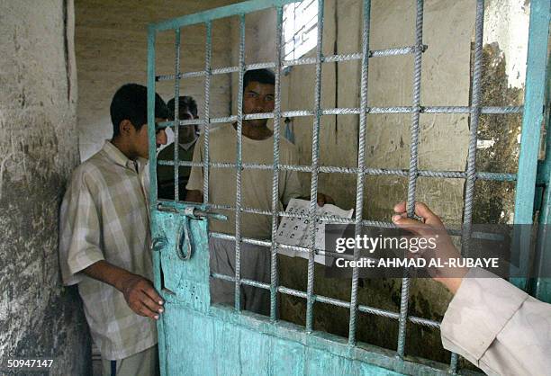 Iraqis holding a print out of prisoners are seen in the detention cell of the Karar police station following clashes between the Mehdi army and Iraqi...