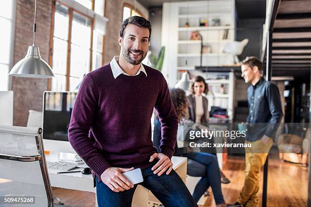 businessman smiling with mobile phone sitting on his desk - european best pictures of the day february 20 2018 stockfoto's en -beelden