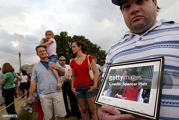 Ed Lilly holds up a picture of former U.S. President Ronald Reagan with his wife Nancy while waiting in line to pay respects to the body of Reagan,...