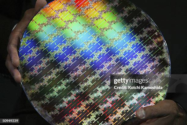 Ajay Malhotra of the Intel Corporation holds a wafer that new Itanium2 processor is made from at a press conference on June 11, 2004 in Tokyo, Japan....