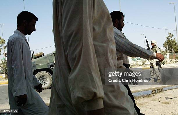 Iraqi civilians walk past soldiers from the 2nd Armoured Cavalry Regiment on patrol on June 11 2004, in downtown Najaf, Iraq. Tensions remain high in...