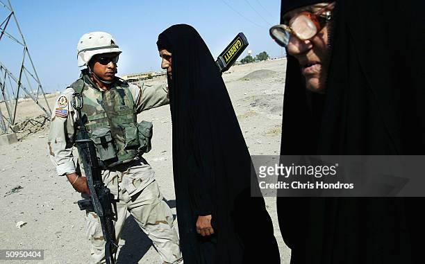Sgt. Luis Rivera of Puerto Rico, with the 2nd Armoured Cavalry Regiment runs a metal detector past Iraqi women at a checkpoint on June 11, 2004 in...