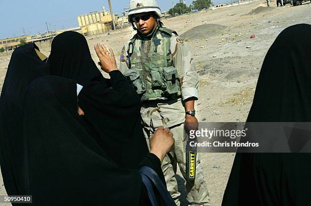 Iraqi women signal to Sgt. Luis Rivera of Puerto Rico, with the 2nd Armoured Cavalry Regiment, after he checked them with a metal detector at a...