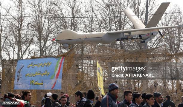 Iranians walk past Iran's Shahed 129 drone during celebrations in Tehran to mark the 37th anniversary of the Islamic revolution on February 11, 2016....