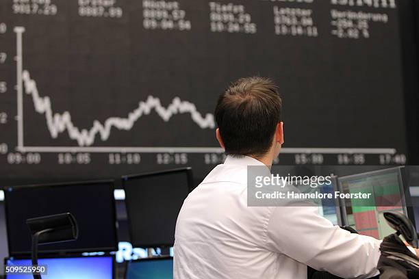 Trader looks up at the board displaying the day's course of the DAX stock market index at the Frankfurt Stock Exchange on February 11, 2016 in...