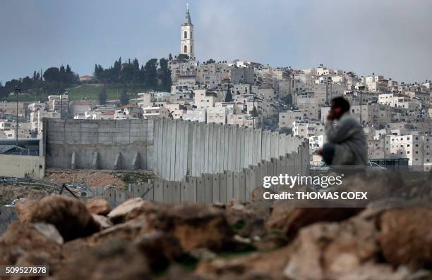 Palestinian man sits near Israel's controversial separation barrier dividing the Palestinian neighbourhood of Al-Tur in the Israeli annexed East...