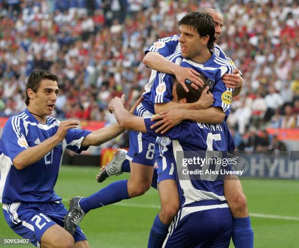 Angelis Basinas of Greece is mobbed after scoring the second goal with a penalty during the Portugal v Greece Group A opening match the 2004 UEFA...