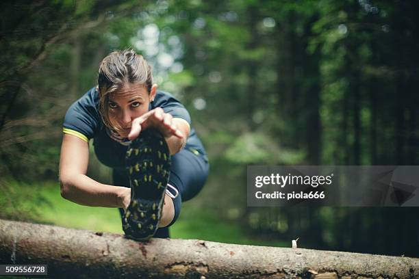woman athlete stretching in the forest after running - strekken stockfoto's en -beelden