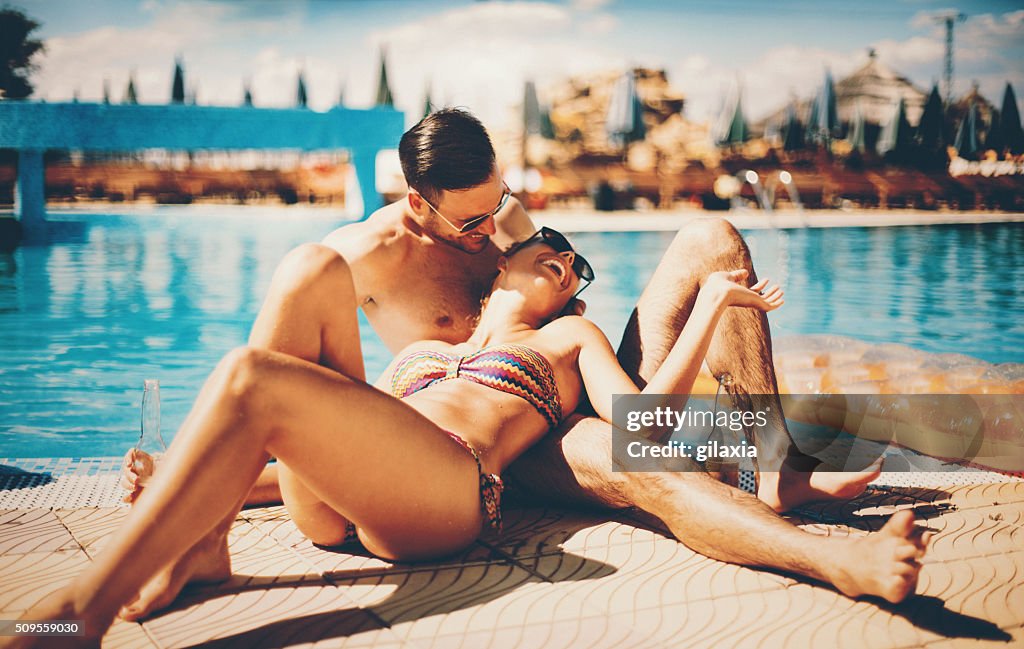 Couple relaxing by swimming pool.