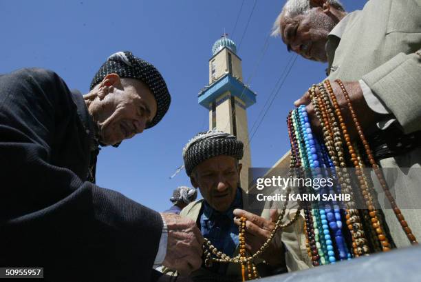 Kurdish men look at prayer beads being sold outside the Suleimaniya Mosque, in the northern Kurdish city of Suleimaniya, 330 kms from Baghdad 13 June...