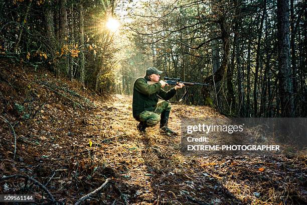 hunter aiming with rifle in the forest - hunter stock pictures, royalty-free photos & images