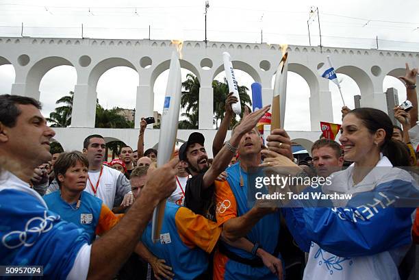 Torchbearer Fernanda Venturini passes the Olympic Flame to Jose Guimaraes in front of Aqueduto during Day 10 of the Athens 2004 Olympic Torch Relay...