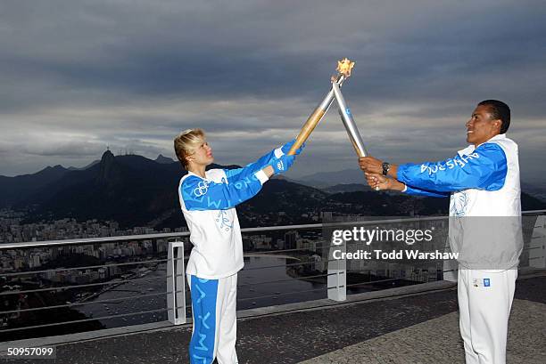 Torchbearer Joaquin Cruz passes the Olympic Flame to Xuxa Meneghel on top of Sugarloaf, overlooking Rio de Janiero, during Day 10 of the Athens 2004...