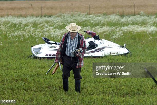 Daniel Landis, the father of Alan Landis, picks up objects near a water craft lying in a field near the home of his son Chris Landis on June 13, 2004...