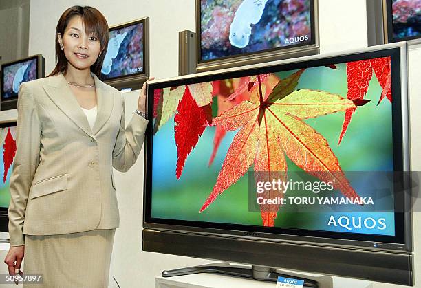 An empolyee of Japan's top-ranked LCD maker Sharp Corp. Shows off the world's largest 45V-inch digital high-definition LCD TV "AQUOS LC-45GD1" in...